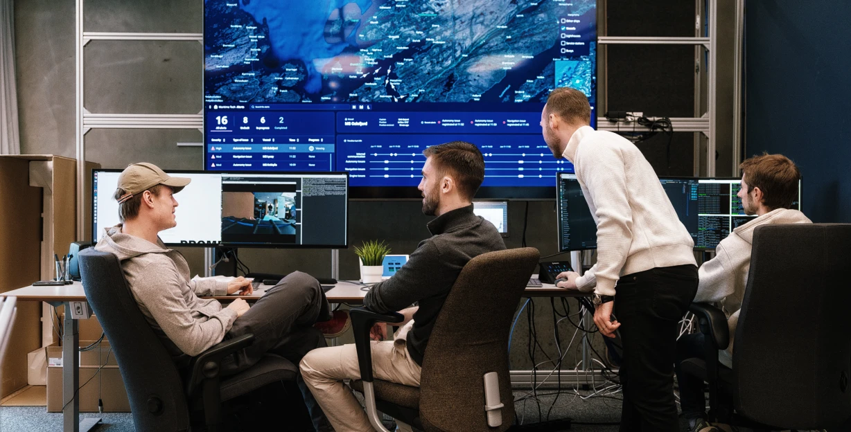 A team at work in front of a large map screen in a control room